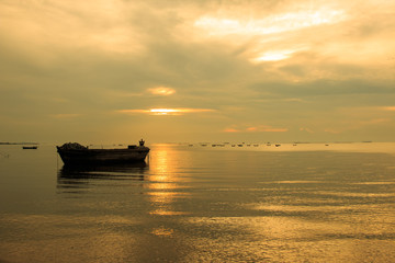 Fototapeta na wymiar old boat in front of sunset background in golden color tone