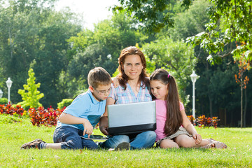 Happy Family using laptop lying on grass