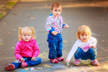 happy children draw with crayons on the pavement in the park