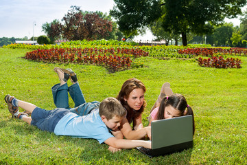 Happy Family using laptop lying on grass
