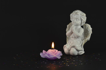 Angel statue object with lit candle isolated on black background 