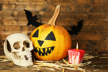 Halloween pumpkin, skull and bloody candles on wooden