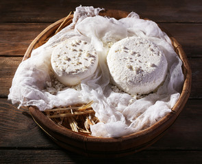Cottage cheese on gauze in wicker basket on wooden background