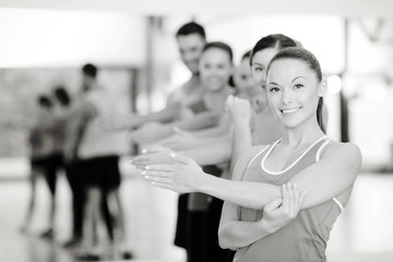group of smiling people stretching in the gym