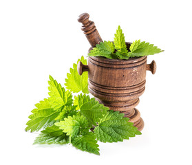 fresh nettle leaves with a mortar on a white background