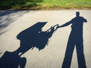 Schattenmann mit Kinderwagen beim Spazieren