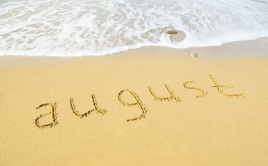 August - written in sand on beach texture