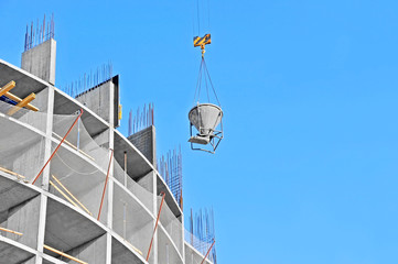 Crane lifting concrete mixer container against blue sky
