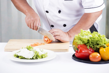 Chef's hands cutting Tomato