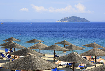 Parasols of straw on the beach and Kelyfos (Turtle) Island