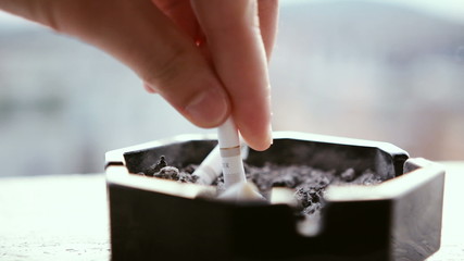 Hand putting off a cigarette in ashtray