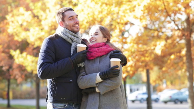 smiling couple with coffee cups in autumn park