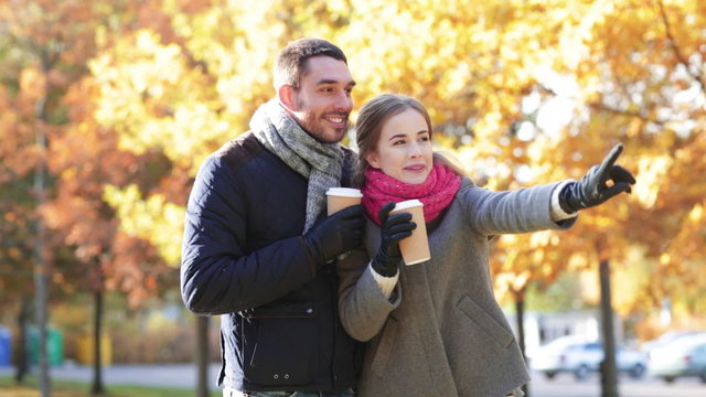 smiling couple with coffee cups in autumn park