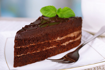 Piece of chocolate cake on plate on light background