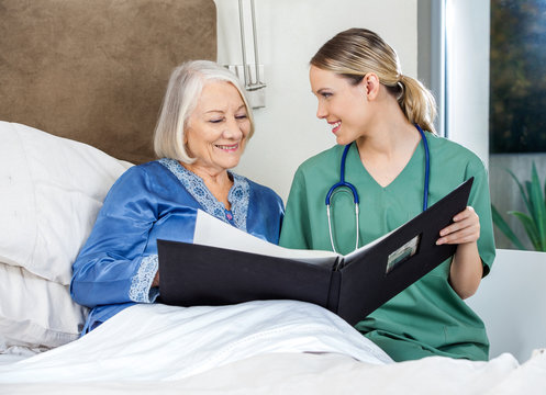Caregiver Showing Medical Reports To Senior Woman