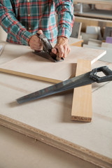 Midsection Of Carpenter Using Planer At Workbench