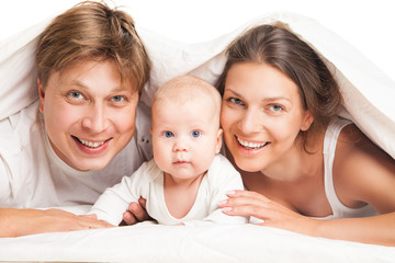 happy family under blanket on the bed at home
