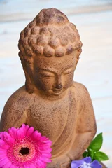 Schilderijen op glas Close-up van Boeddhabeeld met bloemen © trinetuzun