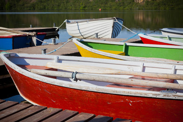 Fototapeta na wymiar Floating Wooden Boats with Paddles in a Lake