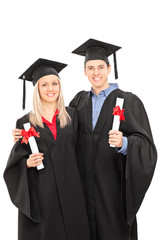 Man and woman in graduation gowns holding diplomas