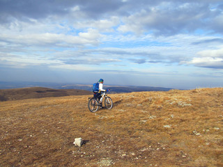 Young athlete standing on a rock with bicycle