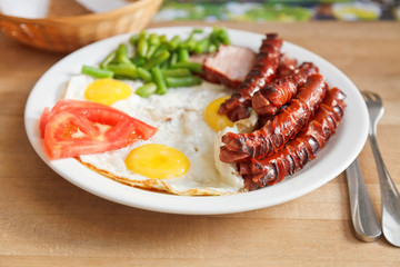 plate with fried eggs, sausages, tomato