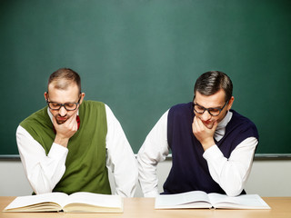 Two male nerds reading book