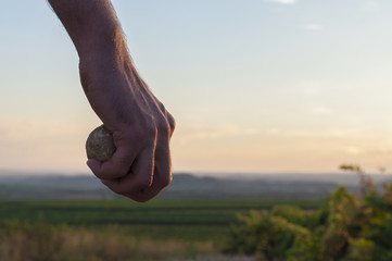 Hand holding a stone. Sky at the background. Sunset - 72253278