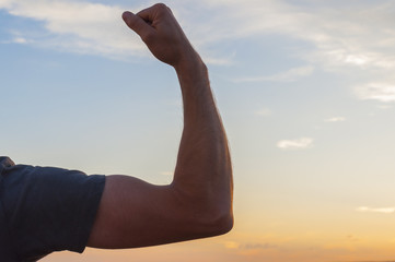 Man posing at sunset, sowing biceps. Nature background