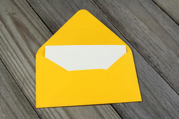 yellow open enveloped with blank card on wooden background