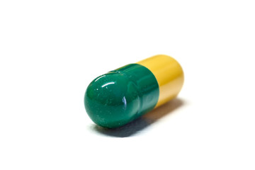 Capsula verde e gialla su sfondo bianco
