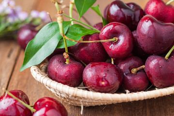 Many fresh cherries in bamboo basket