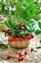 Cowberries in wooden bowl on rustic surface