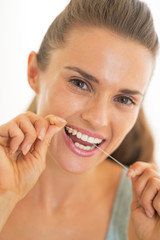 Portrait of young woman using dental floss