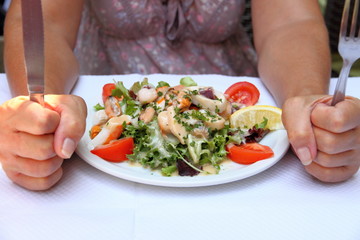 Mediterranean seafood salad and woman with knife and fork