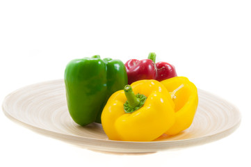 three fresh sweet pepper on wood bowl on white background