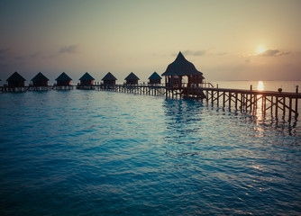 Silhouette of lodges in the sea at sunset. Maldives,