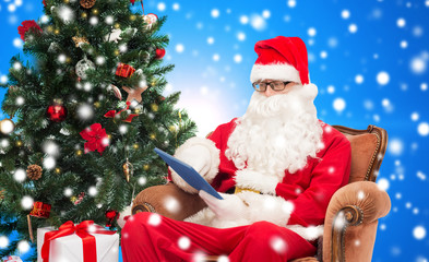 man in costume of santa claus with tablet pc