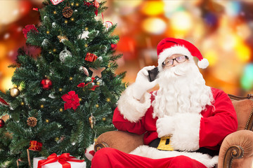 santa claus with smartphone and christmas tree