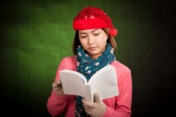 Asian girl with red christmas hat read a book