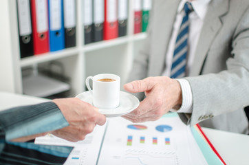 Assistant offering coffee to her boss