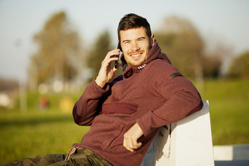 Young Sport Man With Hood Talking On Mobile Phone Outdoors