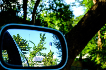 Reflection of trees and buildings. Through the rear view mirror