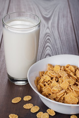 glass of milk and bowl with cornflakes