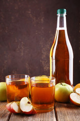 bottle of apple vinegar with fresh apples on wooden table