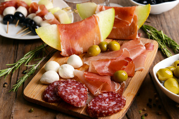 Delicious melon with prosciutto on table close-up