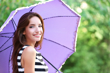 Beautiful young girl with umbrella outdoors