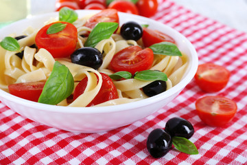 Spaghetti with tomatoes, olives and basil leaves
