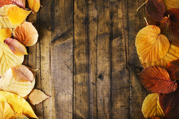 Fototapeta na wymiar Yellow leaves on brown wooden background