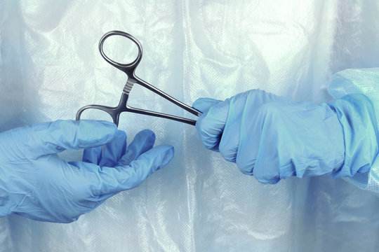 Surgeon's hands holding medical instrument closeup